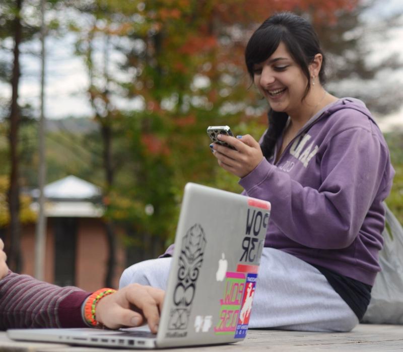 Student outdoors looking at cell phone